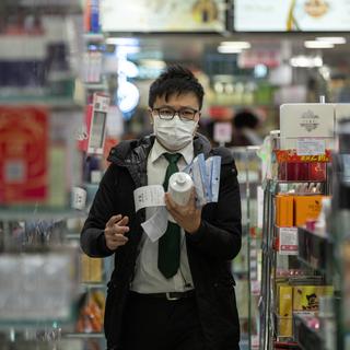 Un client d'une pharmacie à Hong Kong, en pleine épidémie de coronavirus. [Keystone - Jérôme Favre / EPA]