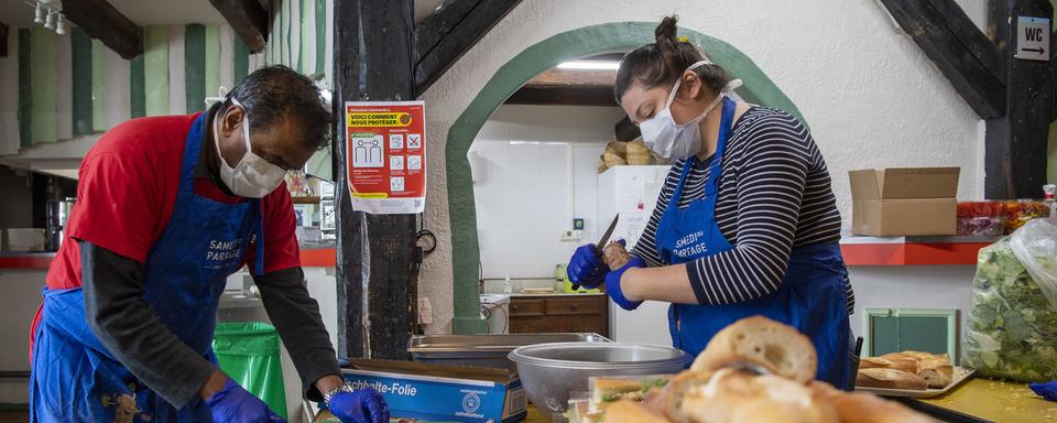 A Genève, des bénévoles du Jardin de Montbrillant de la fondation Carrefour rue  préparent des sandwiches pour offrir aux sans-abri. [Keystone - Martial Trezzini]