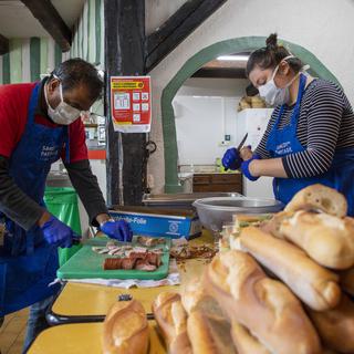 A Genève, des bénévoles du Jardin de Montbrillant de la fondation Carrefour rue  préparent des sandwiches pour offrir aux sans-abri. [Keystone - Martial Trezzini]