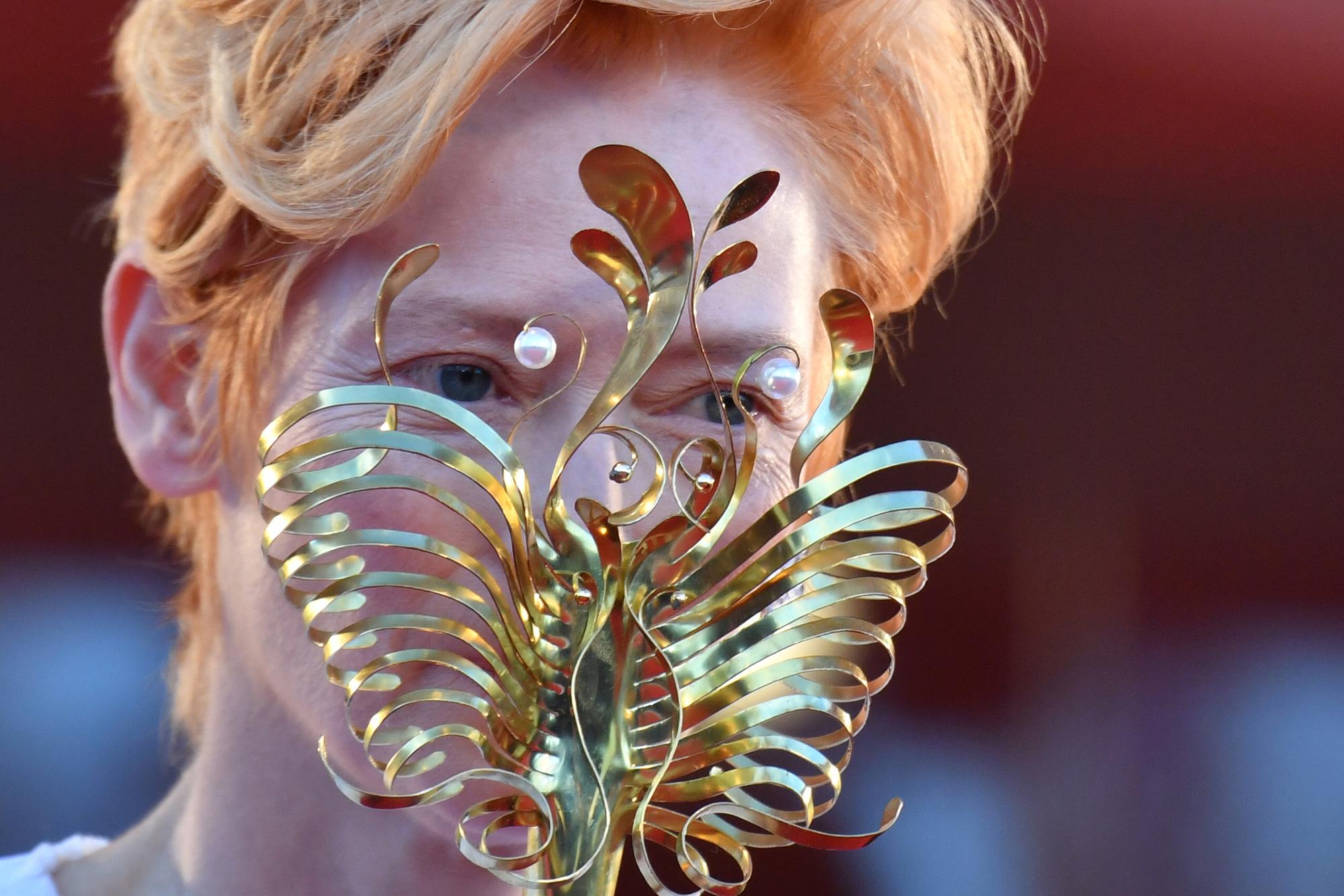 L'actrice britannique Tilda Swinton, qui a reçu un Lion d'Or d'honneur, est arrivée à la cérémonie d'ouverture de la Mostra avec un masque doré dans le style du carnaval vénitien. [AFP - Tiziana Fabi]