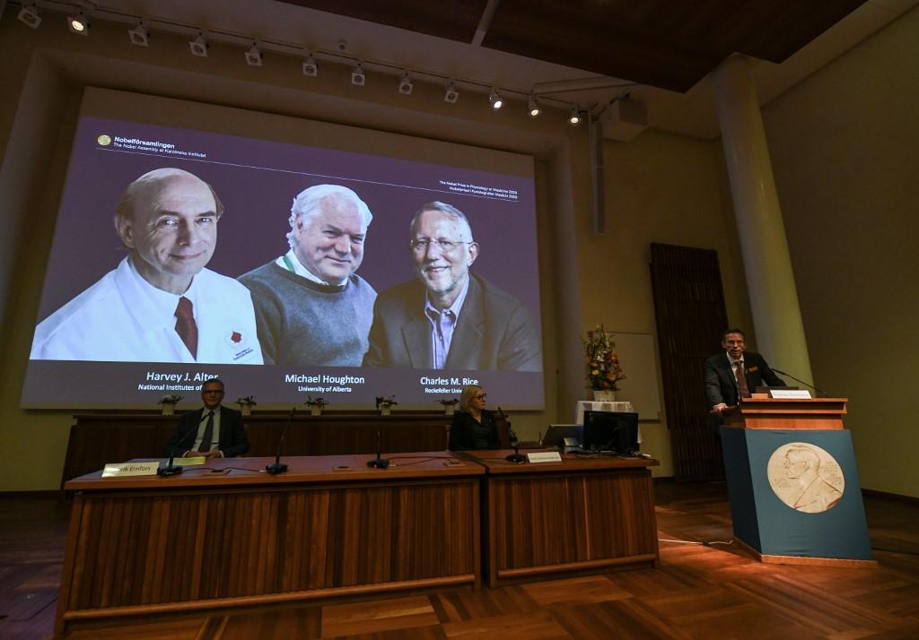 Thomas Perlmann (à droite), le Secrétaire général du Comité Nobel annonce les lauréats du Prix 2020 en médecine ou physiologie: de gauche à droite sur l'écran, l'Américain Harvey Alter, le Britannique Michael Houghton et l'Américain Charles Rice. [AFP - Jonathan Nackstrand]