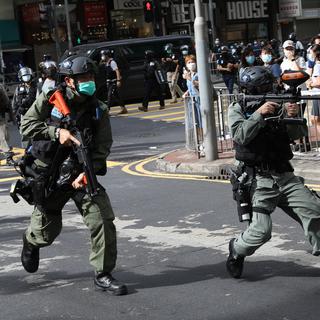 Des policiers prêts à tirer du spray au poivre dans une rue de Hong Kong. [Keystone - EPA / Jérôme Favre]