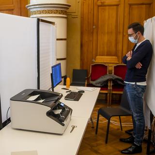 Un scrutateur scanne les bulletins de vote lors des élections communales à Neuchâtel. [Keystone - Jean-Christophe Bott]