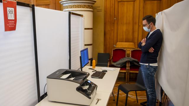 Un scrutateur scanne les bulletins de vote lors des élections communales à Neuchâtel. [Keystone - Jean-Christophe Bott]