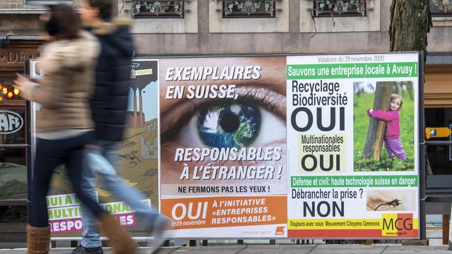 Des personnes passent devant des affiches pour les votations du 29 novembre, notamment l'initiative "entreprises responsables", le 14 novembre 2020 à Genève. [Keystone - Martial Trezzini]