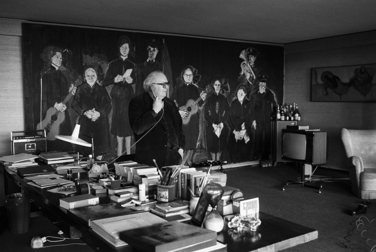 Dürrenmatt dans son bureau de Neuchâtel en décembre 1980, devant la peinture de Varlin "Die Heilsarmee". [Keystone - STR]