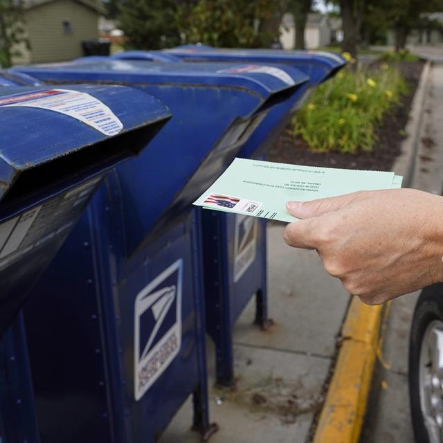 Une personne votant par correspondance depuis son véhicule. [AP Photo/Keystone - Nati Harnik]