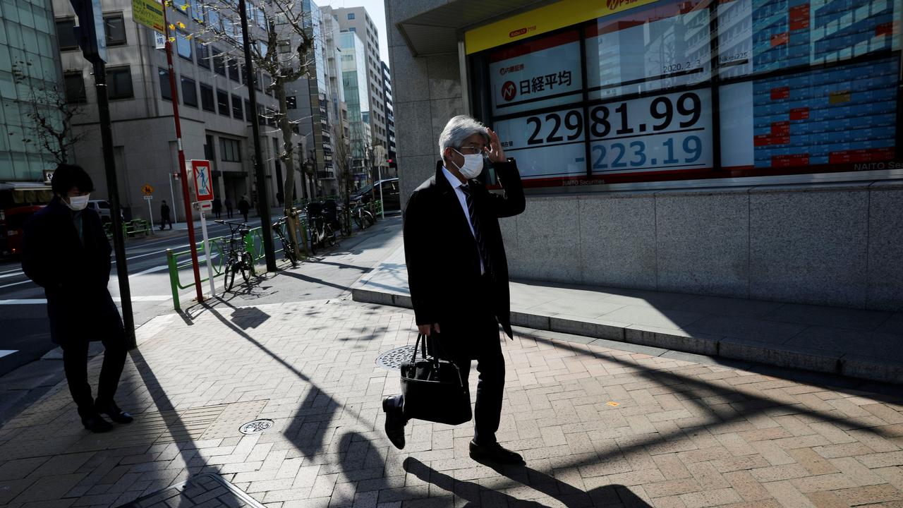 Un homme portant un masque passe devant un écran affichant la valeur de l'indice Nikkei. Tokyo, le 3 février 2020. [Reuters - Kim Kyung-Hoon]