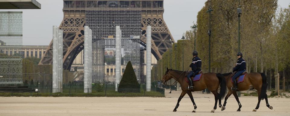 La police montée patrouille dans les environs de la Tour Eiffel à Paris, le 7 avril 2020. [Keystone/epa - Ian Langsdon]