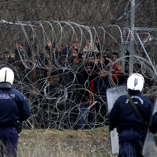 Migrants entassés contre les barbelés face à la police grecque à Kastanies, 04.03.2020. [AP/Keystone - Giannis Papanikos]