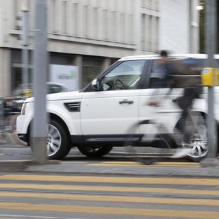 A Range Rover SUV and cyclist in traffic at the intersection Uraniastrasse and Sihlstrasse in Zurich, Switzerland, on March 4, 2019. (KEYSTONE/Gaetan Bally) [Keystone - Gaetan Bally]