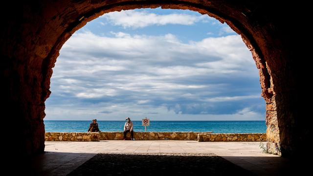 Deux personnes sont assises à distance près de la plage d'Altafulla, à Taragone en Espagne, le 13 mai 2020. [EPA/Keystone - Quique Garcia]