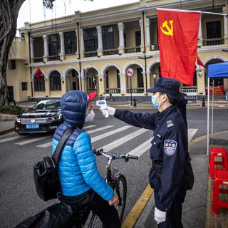 Des gardes de sécurité contrôlent la températures des passants, ce 10 février 2020 à Guangzhou, en Chine. [KEYSTONE - ALEX PLAVEVSKI]