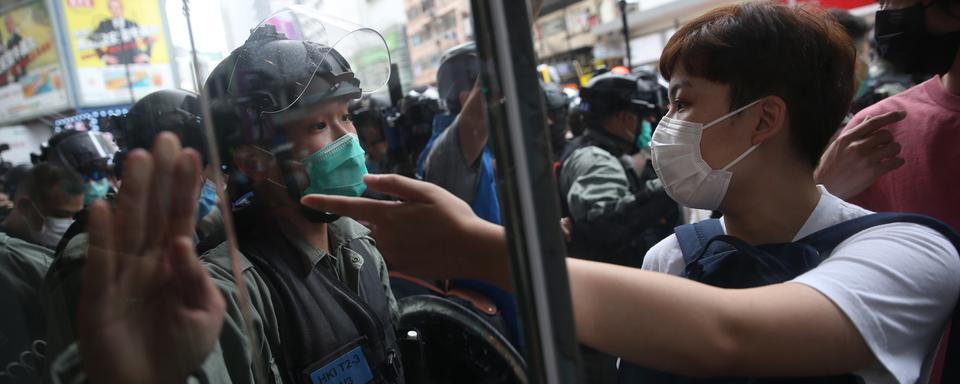 Un manifestant et un policier anti-émeute lors d'une manifestation pro-démocratie, le 24 mai 2020 à Hong Kong. [EPA/Keystone - Jérôme Favre]