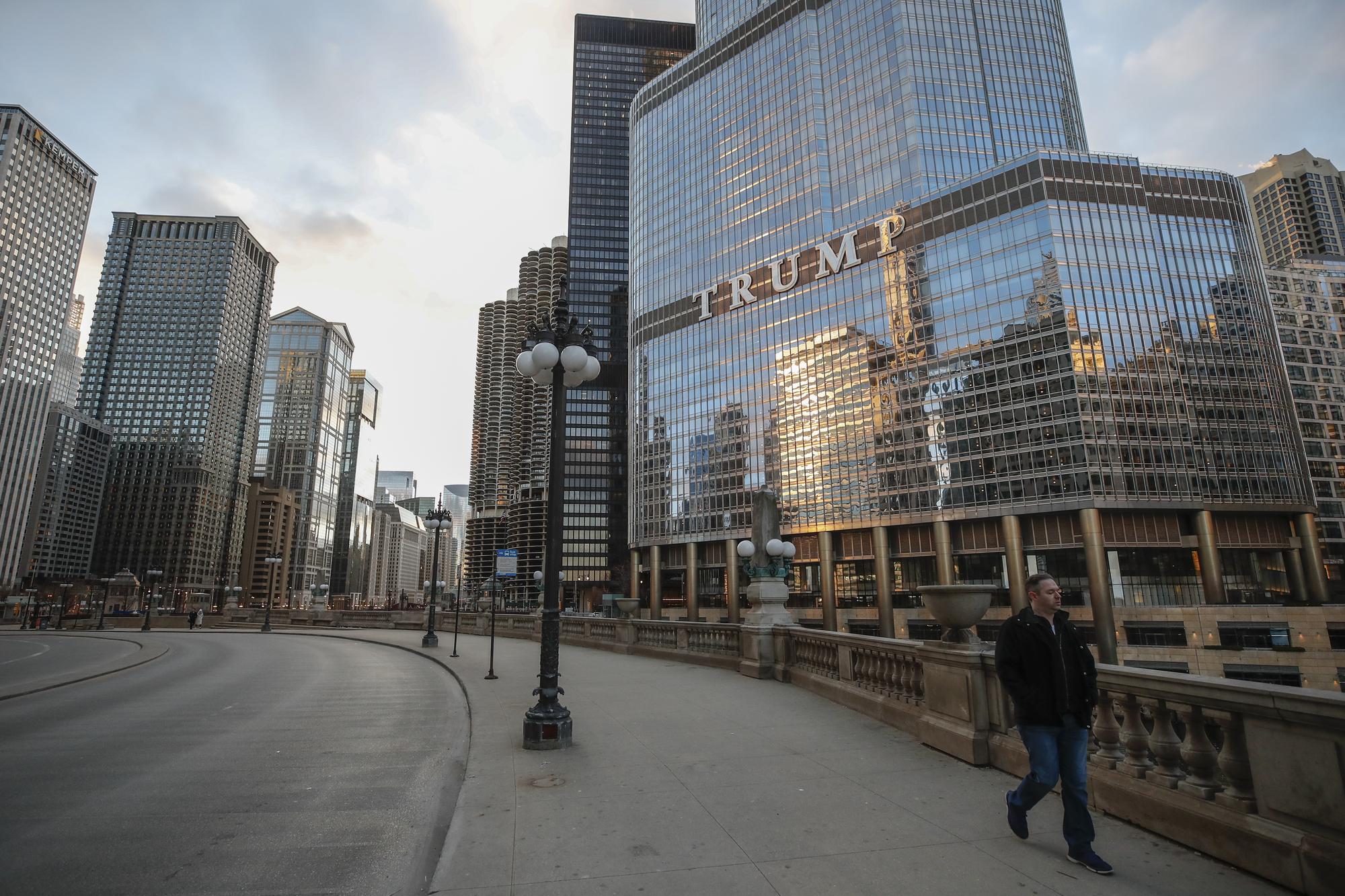 Un homme passe devant la Trump International Hotel and Tower dans les rues presque désertes de Chicago, le 21 mars 2020. [afp - Kamil Krazaczynski]