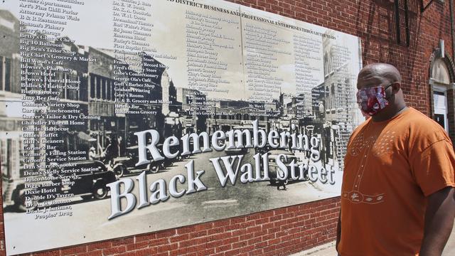 Un homme se tient devant un mur commémoratif du massacre racial de Tulsa, aux Etats-Unis. [AP Photo/Keystone - Sue Ogrocki]