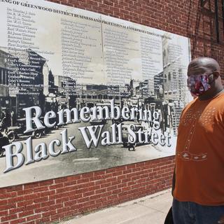 Un homme se tient devant un mur commémoratif du massacre racial de Tulsa, aux Etats-Unis. [AP Photo/Keystone - Sue Ogrocki]