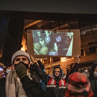 28 novembre 2020, Paris, France: Un manifestant projette les images du tabassage de Michel Zecler par la police dans l'entrée et devant son studio de musique. [AFP - Thomas Morel-Fort / Hans Lucas]