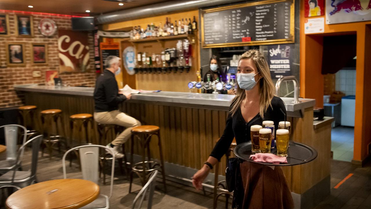 Une serveuse porte des bières à des clients pendant la crise du Coronavirus le mercredi 21 octobre 2020 a Martigny (VS). [Keystone - Jean-Christophe Bott]