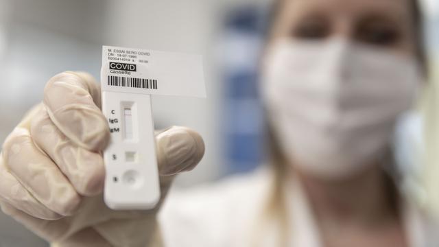 Une laborantine montre un test pour le Covid-19. [Keystone/ap photo - Jean-François Badias]