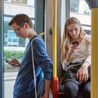 Dans les transports publics, nombreux sont les personnes avec les yeux rivés sur leur smartphone. [KEYSTONE - CHRISTOF SCHUERPF]