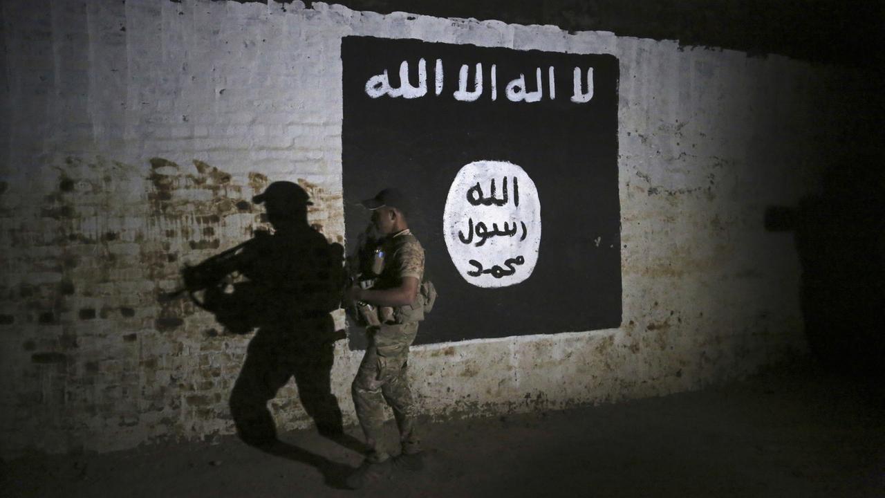 Un soldat irakien devant une bannière du groupe Etat islamique, en 2017 à Mossoul. [AP/Keystone - Khalid Mohammed]