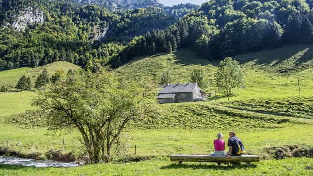 Deux randonneurs font une pause sur un banc à Wasserauen, dans le canton d'Appenzell Rhodes-Intérieures. [Keystone - Melanie Duchene]