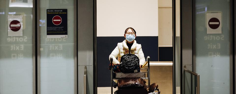 Une passagère arrivant à l'aéroport de Paris Charles de Gaulle en provenance de Pékin. [Keystone - AP Photo/Kamil Zihnioglu]