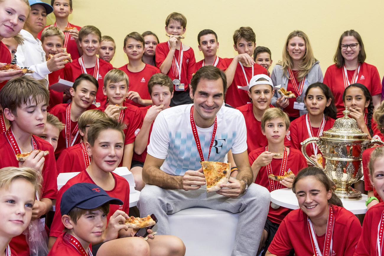 Roger Federer savoure une tranche de pizza avec les ramasseurs de balles des Swiss Indoors; un classique depuis plus d'une décennie. [Keystone - ALEXANDRA WEY]