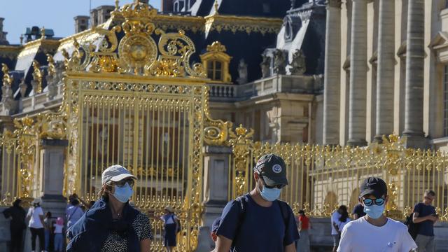 Des touristes portant un masque devant le Château de Versailles. [AP Photo - Michel Euler]