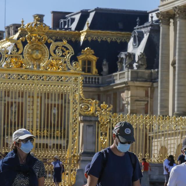 Des touristes portant un masque devant le Château de Versailles. [AP Photo - Michel Euler]