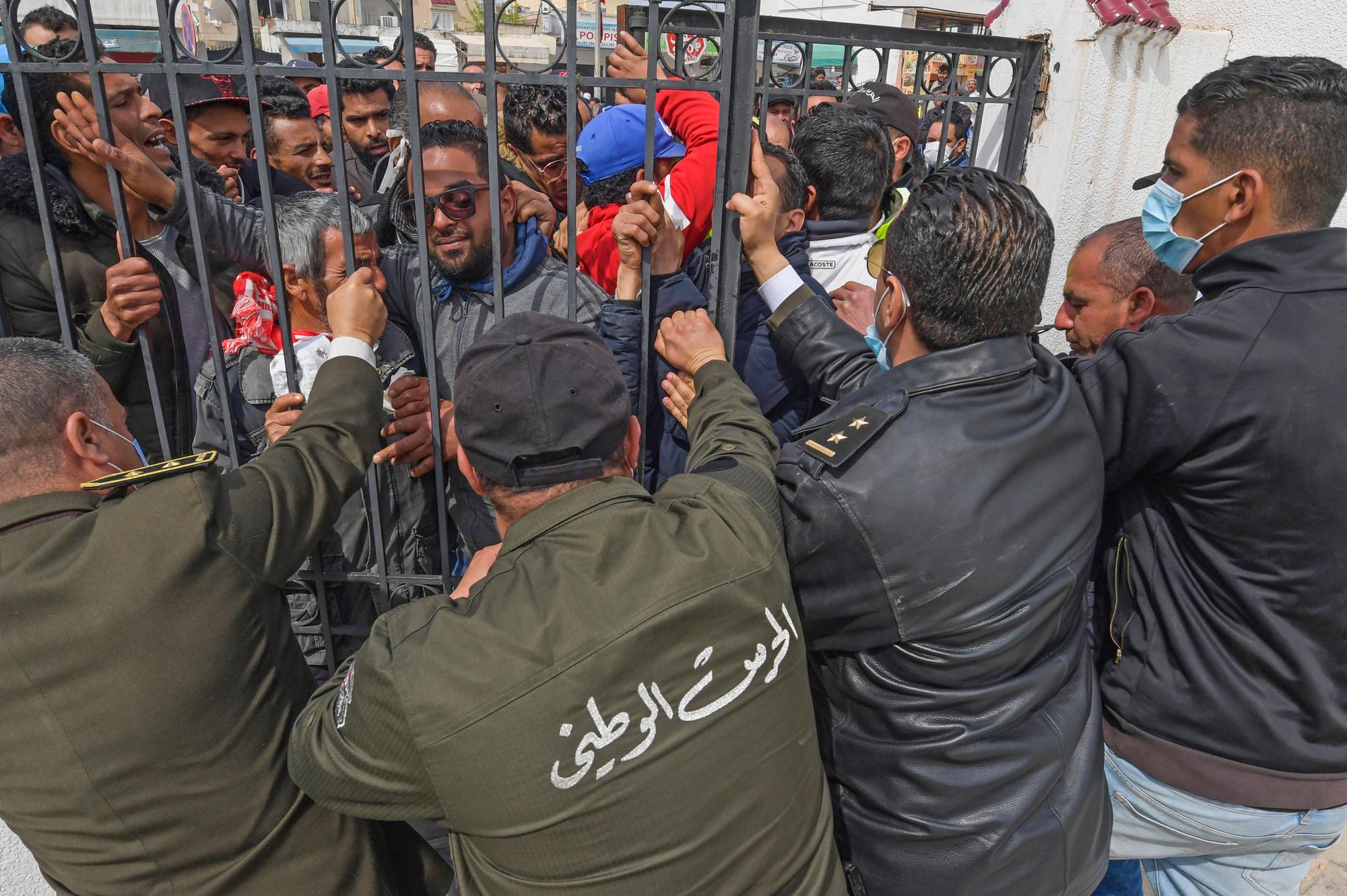 Des personnes manifestent devant la délégation de Mnilha et Ettadhamen, une institution représentant l'Etat dans ces deux quartiers périphérique marginalisés de Tunis, le 30 mars 2020. [AFP - Fethi Belaid]