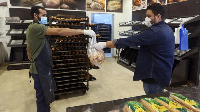 Un client achète du pain en maintenant une distance sociale pour contrer la propagation du Covid-19, dans un supermarché de Tripoli, le 25 mars 2020. [afp - Mahmud Turkia]