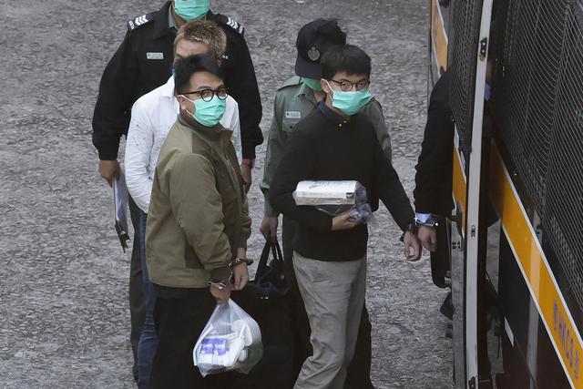 Ivan Lam (à gauche) et Joshua Wong (à droite) sont escorté dans un véhicule carcéral avant d'apparaître devant une court de Hong Kong, le 2 décembre 2020. [Keystone/AP photo - Kin Cheung]