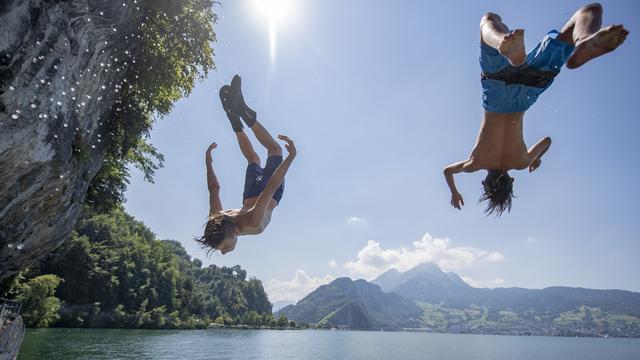 Deux garçons plongent dans le lac des Quatre-Cantons, le 24 juin 2020 à Stans (NW). [Keystone - Urs Flueeler]