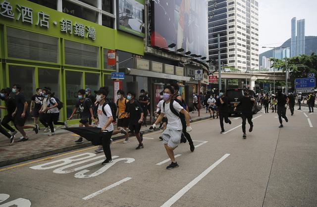 Des manifestants poursuivis par la police dans les rues de Hong Kong, alors qu'ils protestent contre la nouvelle loi de Pékin. [Keystone/AP - Kin Cheung]