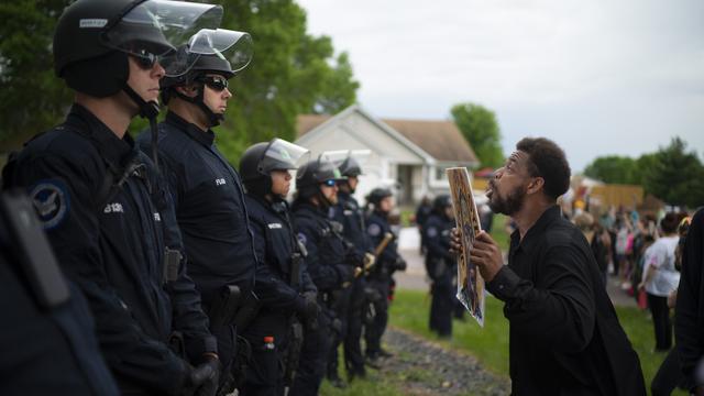 Un manifestant fait face à une ligne de policiers à Minneapolis. [Keystone/Star Tribune via AP - Jeff Wheeler]