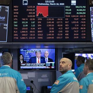 Sur cette photo prise le 18 mars 2020, des traders de Wall Street, la bourse new yorkaise, regardent une conférence télévisée du président Donald Trump. [Keystone - MARK LENNIHAN]