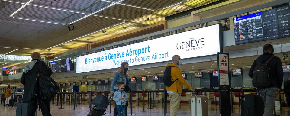 Des personnes attendent avec un masque à l'aéroport de Genève. [Keystone - Salvatore Di Nolfi]