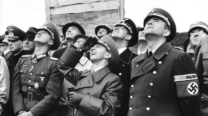 Hauts gradés et dirigeants nazis dont Joseph Goebbels (au centre) et l'architecte du Reich Albert Speer (avec le brassard à croix gammée) à Peenemünde, en août 1943. [Das Bundesarchiv]