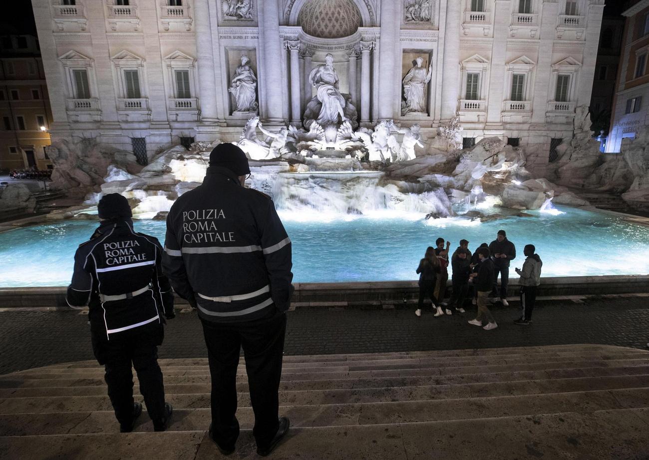 Des policiers regardent quelques jeunes assemblés devant la Fontaine de Trevi, Rome le 8 mars 2020. [Keystone/epa - Massimo Percossi]