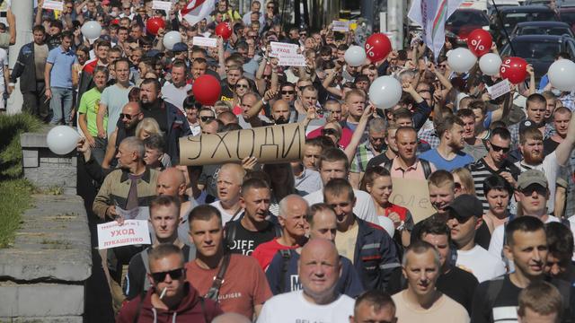 Des travailleurs en grève marchent en direction de l'usine de tracteurs de Minsk où le président biélorusse Alexandre Loukachenko prononce un discours. [Keystone/AP Photo - Dmitri Lovetsky]