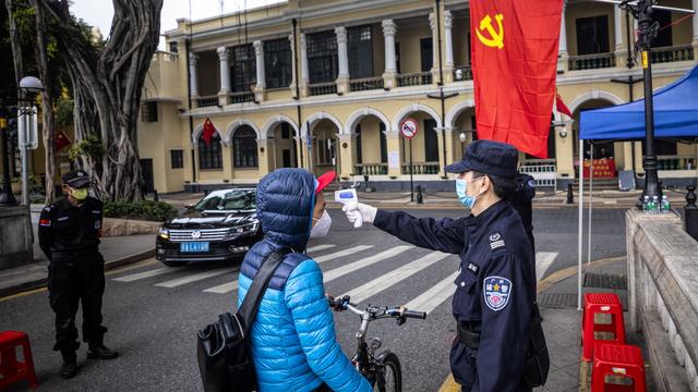 Des gardes de sécurité contrôlent la températures des passants, ce 10 février 2020 à Guangzhou, en Chine.