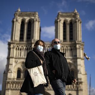 Deux personnes portant un masque devant la cathédrale Notre-Dame. [Keystone/EPA - Ian Langsdon]
