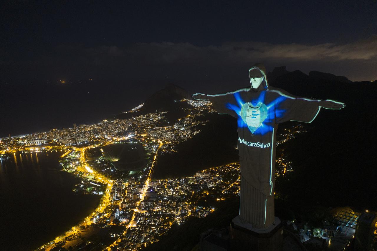 L'iconique statue du Christ Rédempteur illuminé de façon à porter un masque et proclamer le slogan "Le masque sauve". Rio de Janeiro, le 3 mai 2020. [Keystone/AP photo - Leo Correa]