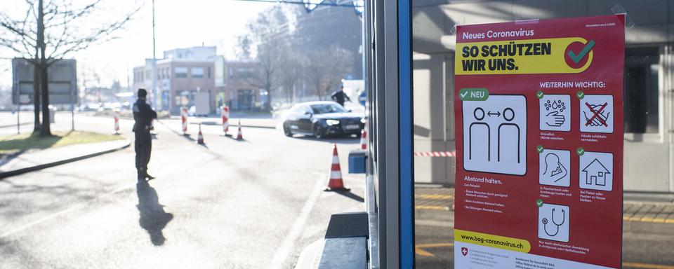 Une affiche de prévention pour le coronavirus à un poste de frontière. [Keystone - Ennio Leanza]