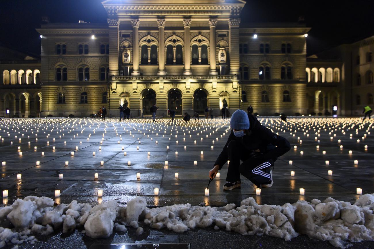 La place fédérale se couvre certains soirs de bougies pour commémorer les personnes disparues, comme ici le 6 décembre 2020. [KEYSTONE - Anthony Anex]