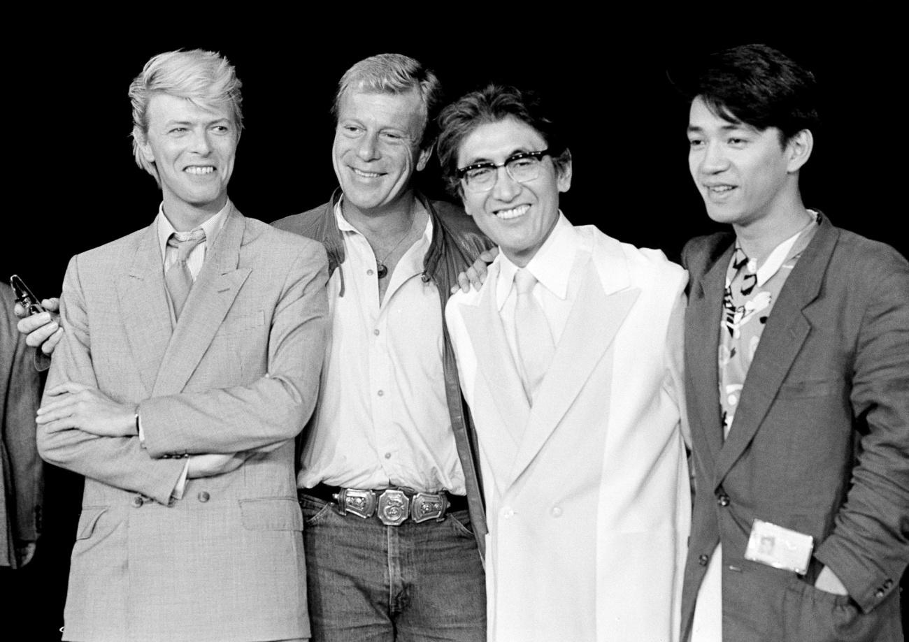 De gauche à droite: L'acteur David Bowie, le producteur Jack Thomas, le réalisateur Nagisa Oshima et l'acteur et compositeur Ryuichi Sakamoto. Pour le film "Merry Christmas, Mr. Lawrence" ("Furyo"), à Paris en mai 1983. [AP/AFP - Jacques Langevin]