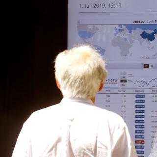 Un homme regarde les résultats du marché boursier dans un bureau d'une banque zurichoise. [Reuters - Arnd Wiegmann]