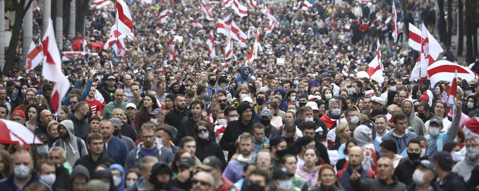 Des personnes portant d'anciens drapeaux nationaux biélorusses ont défilé lors d'un rassemblement de l'opposition pour protester contre les résultats officiels de l'élection présidentielle à Minsk, en Biélorussie, ce dimanche 27 septembre 2020. [keystone - tut.by]